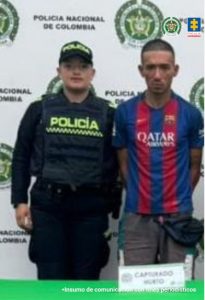 En la fotografía se aprecia de pie y con los brazos atrás a Juan David Hurtado Mejía. Viste con camiseta de un equipo europeo de fútbol con franjas verticales azules y rojas; así como pantalón gris. Al lado derecho de él hay un uniformado de la Policía Nacional y detrás de ellos hay un pendón institucional de la Policía.
