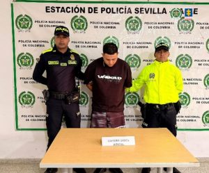 En  la fotografía aparece de pie y con los brazos atrás, Juan José Agudelo Sepúlveda. Viste con camiseta de color negro, mangas cortas y estampado blanco en el pecho; pantalón negro desgastado y con estampado blanco a la altura del muslo izquierdo. En los extremos hay uniformados de la Policía Nacional. Delante de ellos hay una superficie y sobre ella hay un letrero que dice: ‘Captura orden judicial’. Detrás de ellos hay un pendón institucional de la Policía.