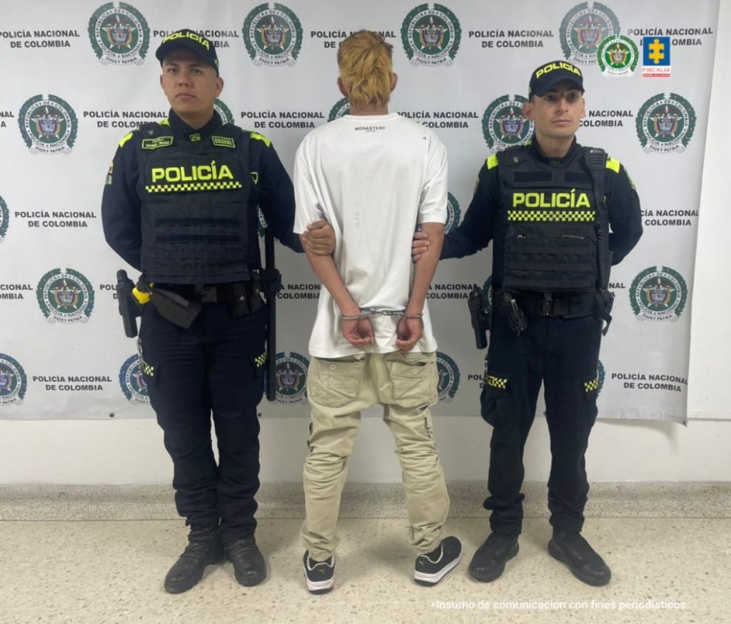 Juan Manuel Molano Salazar está en la foto con dos funcionarios de la Policía Nacional y atrás el pendón de la misma institución.