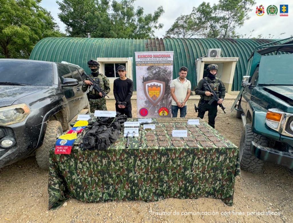 Se visualiza a los capturados junto a uniformados del Ejército y Policía Nacional, frente a ellos una mesa con el material de guerra y vehículos incautados. Detrás el banner que identifica al Ejército Nacional.