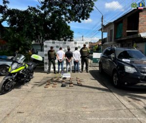 La fotografía es en un exterior y se aprecian de pie, con los brazos atrás, esposados y de espaldas a la cámara a los tres presuntos implicados de transportar cerca de 10 kilos de marihuana. A sus extremos hay uniformados de la Policía Nacional. Asimismo, hay un vehículo, tipo camioneta de placas KIJ 374. En el suelo hay 20 paquetes y un letrero que dice: ‘Marihuana’. En la parte posterior hay un pendón institucional de la Policía.