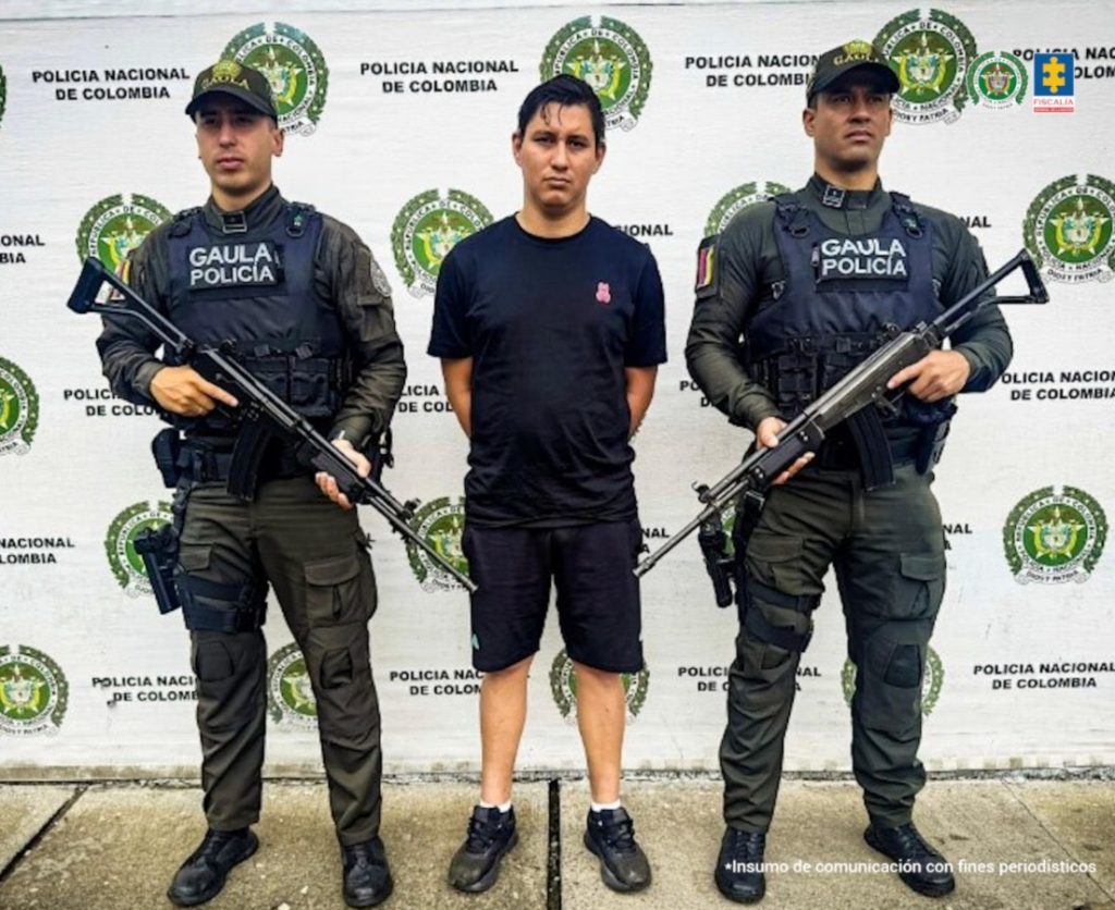 En la fotografía aparece de pie y con los brazos atrás Julián Andrés Benito Forero. Viste con camiseta de manga corta, pantaloneta y zapatillas de color negro. A sus extremos hay uniformados del grupo Gaula de la Policía Nacional. Detrás de ellos hay un pendón institucional de la Policía.