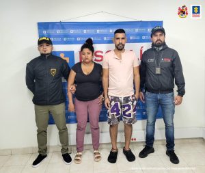 Se observan una mujer y un hombre, ambos capturados y de frente. En un costado un funcionario de CTI y al otro uno del Ejército Nacional. Atrás un pendón de la Fiscalía General de la Nación