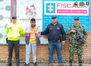 en la imagen se ve una persona detenida bajo custodia de un investigador del CTI, un integrante de la Policía y otro del Ejército.