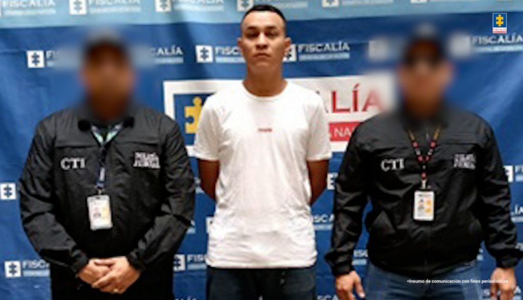 En la imagen aparece una persona de suéter blanco, entre dos uniformados del CTI. 