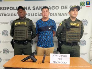 En la fotografía se aprecia de pie y con los brazos atrás a Kevin Jhoan Osorio Chavarro. Viste camiseta azul, de manga corta, con estampados negros y una franja gruesa de color negro a la altura del pecho; pantalón caqui. A sus extremos hay uniformados de la Policía Nacional. Delante de ellos hay una superficie café clara y sobre ella hay un arma de fuego, un proveedor y munición. Asimismo, un letrero que dice: ‘Capturado por feminicidio’. Detrás de ellos hay un pendón institucional de la Policía.