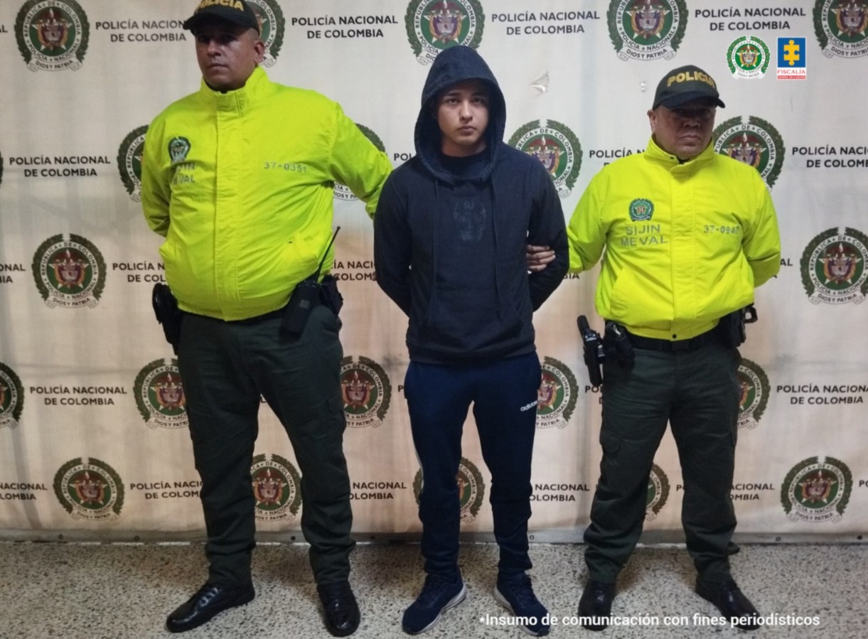 En la imagen está e procesado con chompa azul oscura y 2 uniformados de la Policía Nacional a los lados