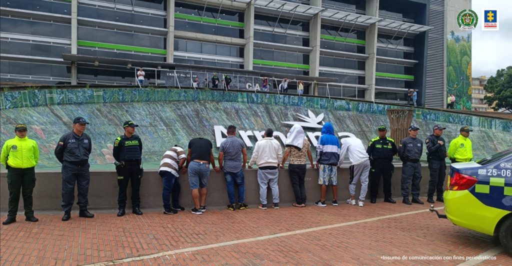 Se observan siete detenidos de espaldas en fila. A un costado un funcionario de CTI y dos de Policía Nacional. Al otro costado dos funcionarios de CTI y dos de Policía