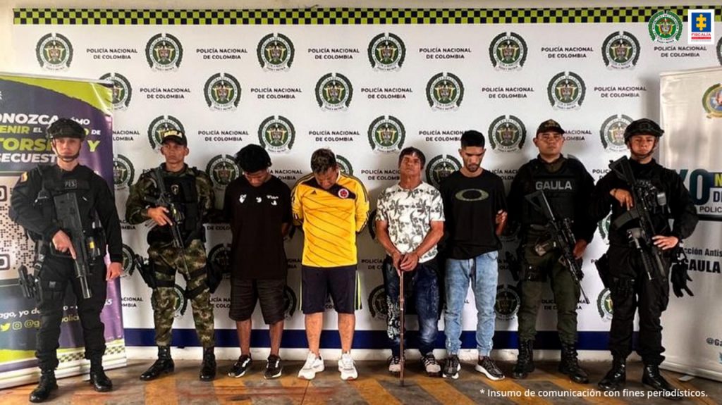 Se observan cuatro personas detenidas y a cada costado dos funcionarios del Gaula Policía. En la parte posterior un baking de Policía Nacional
