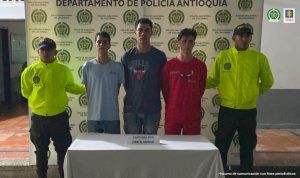 En la imagen se encuentra el menor judicializado de espaldas y la parte de la cabeza distorsionada, con dos servidores de la Policía Nacional a sus lados