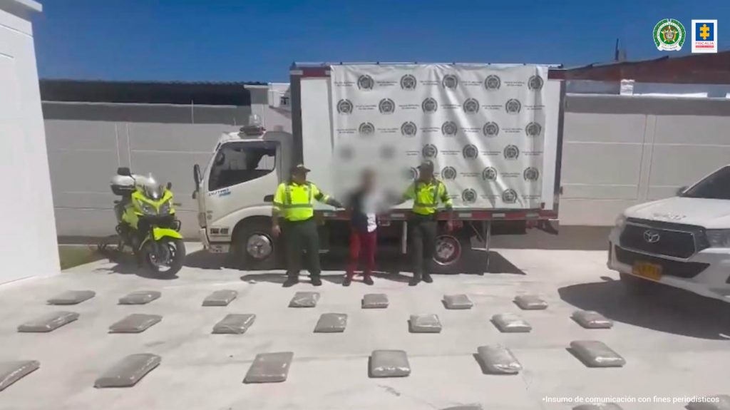 en la foto se aprecia al hoy asegurado siendo custodiado por la Policía y con los paquetes de estupefacientes incautados.