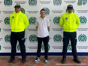 Fiscal Martha Mancera, Martha Mancera, Fiscal Mancera Se observa al capturado de frente y en cada costado un uniformado de Policía Nacional. Atrás un pendón de Policía Nacional