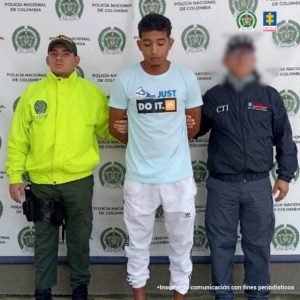 En la fotografía aparece el capturado junto a un servidor del CTI y un agente de la Policía Nacional. En la parte superior está un banner de la Policía Nacional