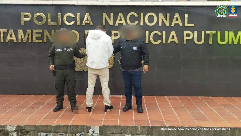 En la fotografía aparece un hombre capturado, acompañado de un servidor del CTI y un uniformado de la Policía Nacional. En la parte posterior un banner con logos de la entidad.