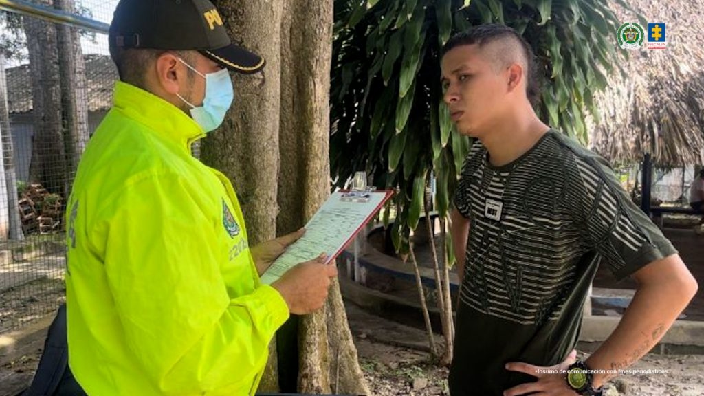 En la imagen aparece una persona frente a un policía quien le lee un documento.