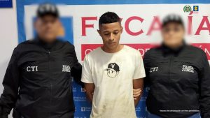 En la imagen aparece una persona de suéter blanco entre dos uniformados del CTI.