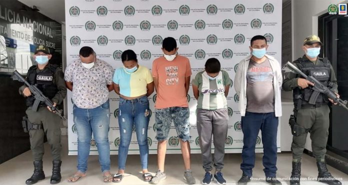 En la imagen se ven cinco personas detenidas, entre dos policías del Gaula.