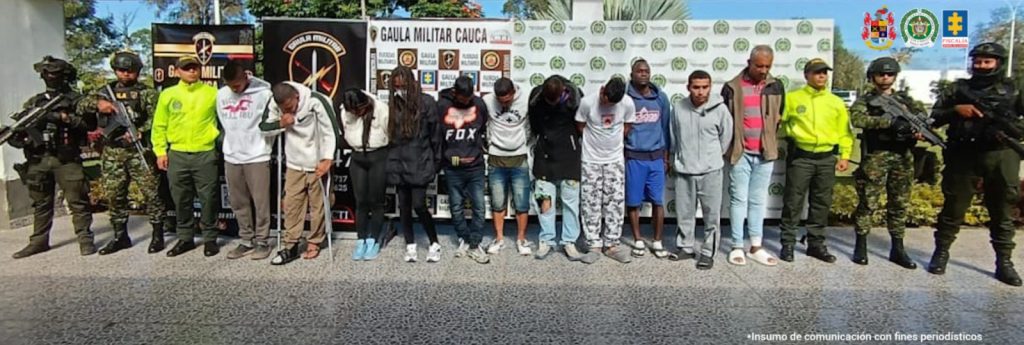 En la fotografía aparecen 11 capturados junto dos uniformados de la Policía Nacional y dos soldados del Gaula Militar. En la parte superior están un banner de la Policía Nacional y otros dos banners del Gaula militar.