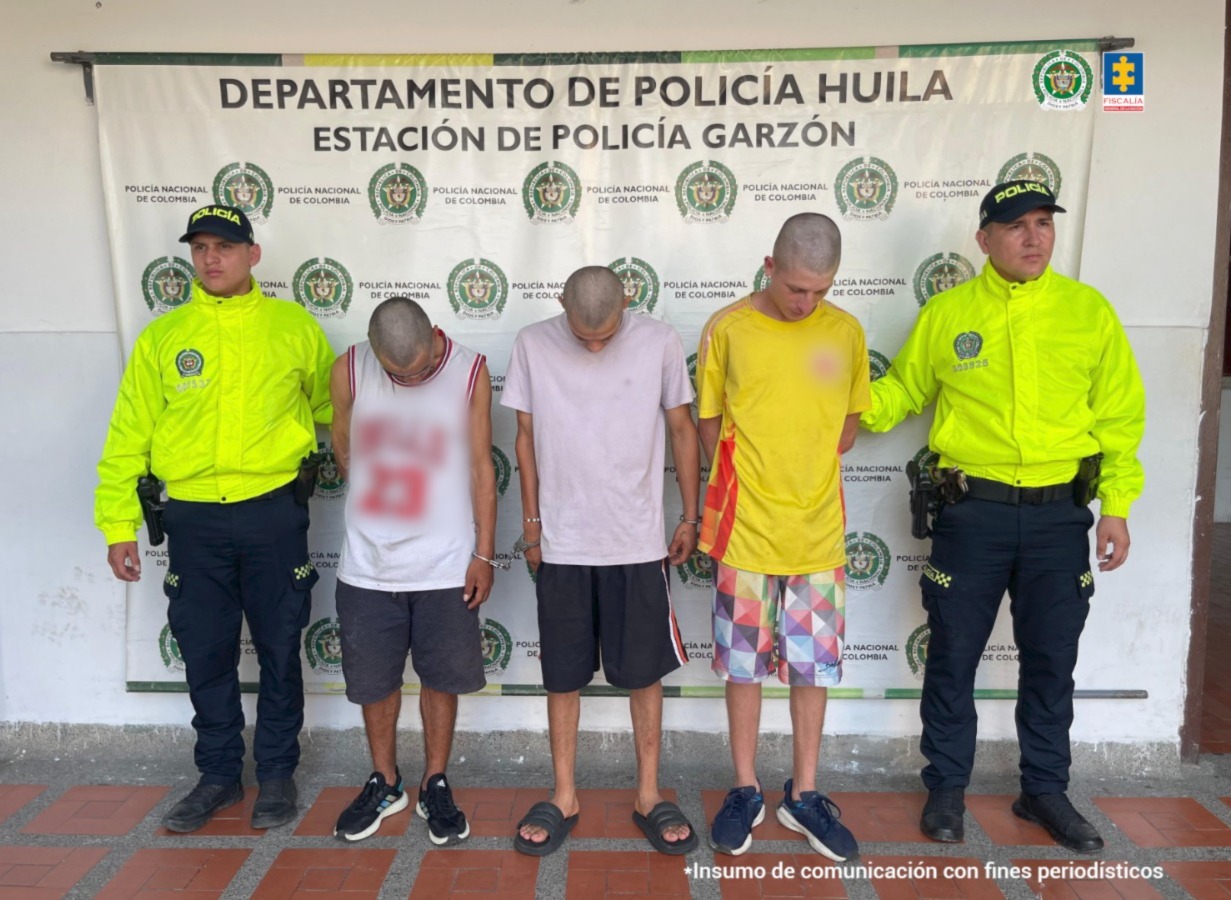 Los tres capturados se encuentran de frente y con la cabeza abajo, custodiados por uniformados de la Sijin de la Policía Nacional.