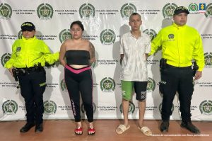 En la foto se observa a la pareja custodiada por dos uniformados de la Policía Nacional. También se observa detrás un backing de la Policía Nacional.