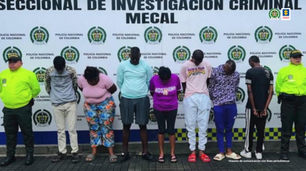 En la foto aparecen los presuntos integrantes del grupo delincuencial Los Oviedo. A lado y lado de ellos hay uniformados de la Policía Nacional. Detrás de ellos se aprecia un pendón institucional de la Policía.