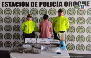Desarticulada banda delincuencial dedicada a comercializar estupefacientes en Casanare capturados en dos fotografías, una con un solo detenido y la otra con seis, de espaldas y esposados, custodiados por uniformados de la Policía Nacional, delante de ellos el material incautado sobre una mesa, detrás banner de la Policía Nacional.