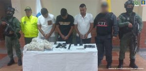 En la fotografía aparecen los tres capturados junto a dos agentes de la Policía Nacional. En la parte posterior se observa una mesa con estupefacientes, un arma, binoculares y tres teléfonos celulares
