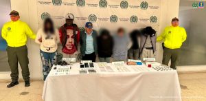 En la fotografía aparecen los tres asegurados juntos a dos agentes de la Sijin de la Policía Nacional. En la parte posterior está una mesa con dos armas de fuego, munición, dosis de estupefacientes y dos grameras para pesar dosis
