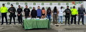 En la fotografía aparecen los cuatro detenidos junto a dos servidores del CTI y cuatro uniformados de la Policía Nacional. En la parte posterior está una mesa con un arma de fuego, munición, estupefacientes, teléfonos celulares, grameras y bolsas para empacar cigarrillos de marihuana.