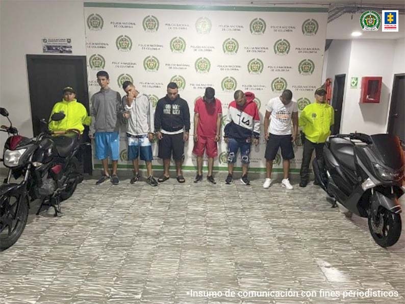 En la foto aparecen seis presuntos integrantes de ‘Los Visitors’. Al lado derecho e izquierdo de ellos hay dos uniformados de la Policía Nacional y dos motocicletas. Detrás de ellos hay un pendón institucional de la Policía Nacional. 