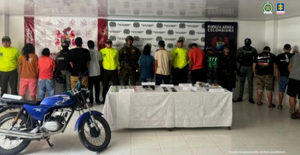 Los imputados se encuentra de espalda y en custodia por uniformados del Gaula del Ejército y de la Policía Nacional. Detrás se observa un backing del Ejército y de la Policía Nacional.