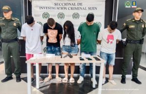 Se visualiza a los capturados junto a dos uniformados de la Policía Nacional. Frente a ellos los elementos incautados. Detrás de ellos el banner que identifica a la Policía Nacional.