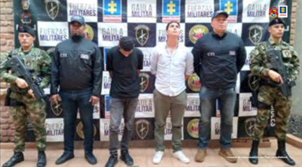 En la fotografía se aprecian de pie y con los brazos atrás a Luis Ánderson Paz Castillo y Andrés Felipe Herrera Jiménez. Uno de ellos tiene la cabeza agachada, viste camisa negra de manga corta, pantalón gris y zapatos oscuros. El otro mira hacia arriba y viste camisa blanca con mangas dobladas a la altura de los codos; pantalón verde y zapatos blancos. A lado y lado de ellos hay servidores del CTI de la Fiscalía y del Ejército Nacional. Detrás de ellos hay un pendón interinstitucional con los logos de la Fiscalía, Ejército y del Gaula Militar.