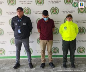En la foto aparece, de pie, cabeza agachada, con los brazos atrás Luis Ángel Arias Betancourt, alias Barragán. Usa tapabocas azul; viste camisa de manga corta color vinotinto, pantalón color caqui y zapatos negros. Al lado derecho de él hay un servidor del CTI y al lado izquierdo una uniformada de la Policía Nacional. Detrás de ellos hay un pendón institucional de la Policía.