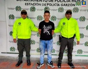 El procesado se encuentra esposado y en custodia por uniformados de la Policía Nacional. Detrás suyo un backing de la Policía.