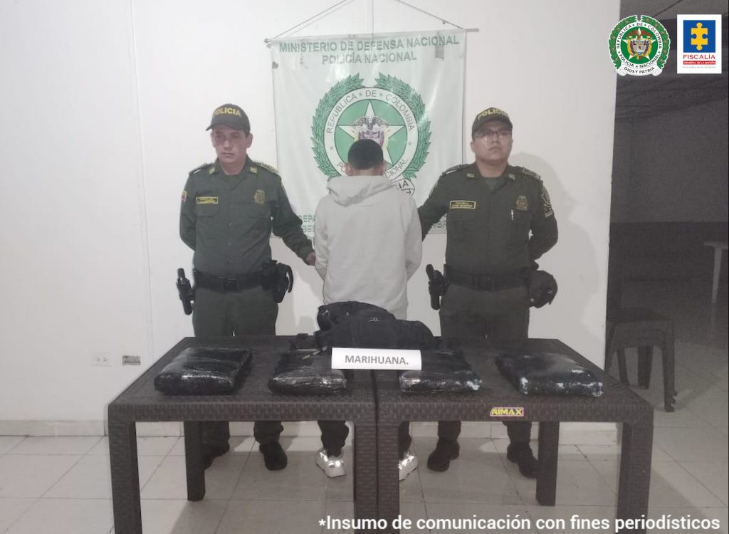 En la fotografía aparece un capturado, junto a personal de Policía Nacional. En la parte posterior de la imagen se ven banners de Policía Nacional y la Fiscalía General de la Nación.