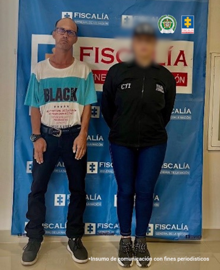 En la fotografía se aprecia de pie y con los brazos a los lados a Luis Eduardo Posada. Viste camiseta de manga corta de color blanca con franja ancha horizontal de color azul claro; pantalón y zapatos negros. A su extremo izquierdo hay una servidora del CTI de la Fiscalía. Detrás de ellos hay un pendón institucional de la Fiscalía.