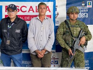 En la imagen se ve una persona detenida entre dos uniformados del CTI y de la Armada.