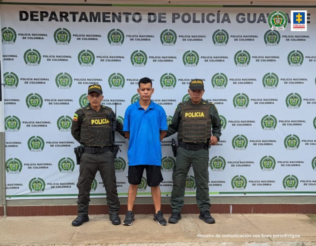 En la foto aparece Luis Felipe Peralta Rueda con dos policías a los lados y atrás el pendón de la Policía Nacional con logos.