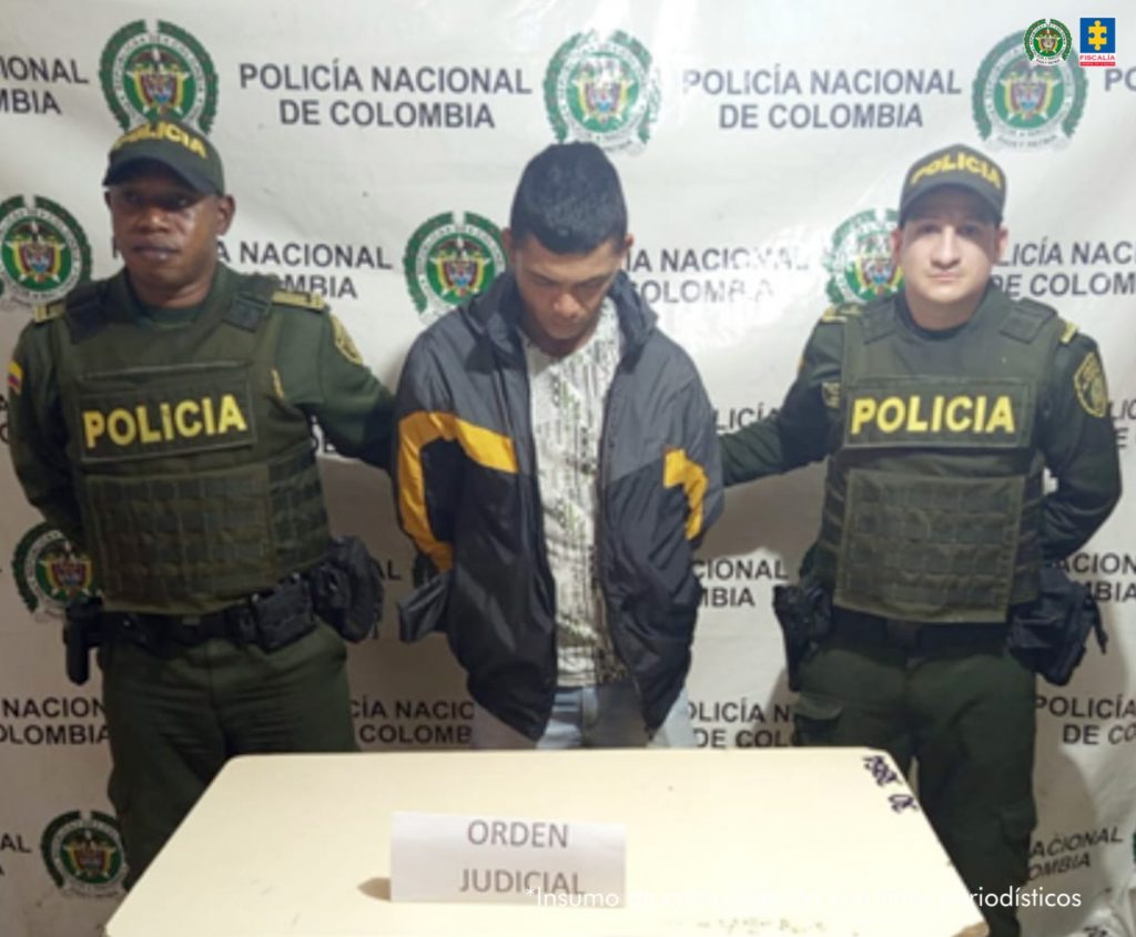 En la fotografía aparece de pie, con los brazos atrás y la cabeza agachada Luis Felipe Pérez Vélez. Viste chaqueta negras con franja de color naranja en mangas y a la altura del pecho. Debajo de la chaqueta usa una camisa clara con estampado verdoso, así como jean claro. A los extremos de él hay uniformados de la Policía Nacional. Delante de ellos hay una superficie blanca y sobre ella hay un letrero que dice:  ‘Orden judicial’. Detrás de ellos hay un pendón institucional de la Policía.
