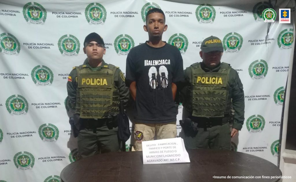 En la imagen aparece una persona detenida, con suéter negro, entre dos uniformados de Policía.