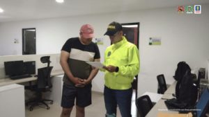 En la fotografía aparece un capturado junto a personal de Policía Nacional. En la parte posterior de la imagen se ven banners de Ejército Nacional, Policía Nacional y la Fiscalía General de la Nación.