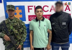 En la imagen aparece una persona de suéter verde, entre dos uniformados del CTI y el Ejército Nacional. 