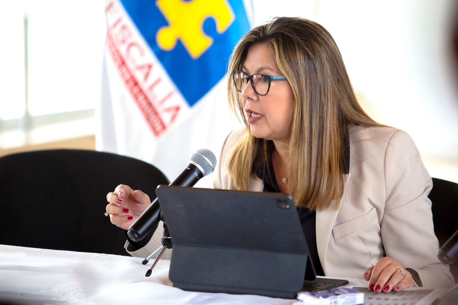 En la imagen puede verse a la Fiscal General, Luz Adriana Camargo, hablando ante un micrófono. Al fondo la bandera de la Fiscalía. 