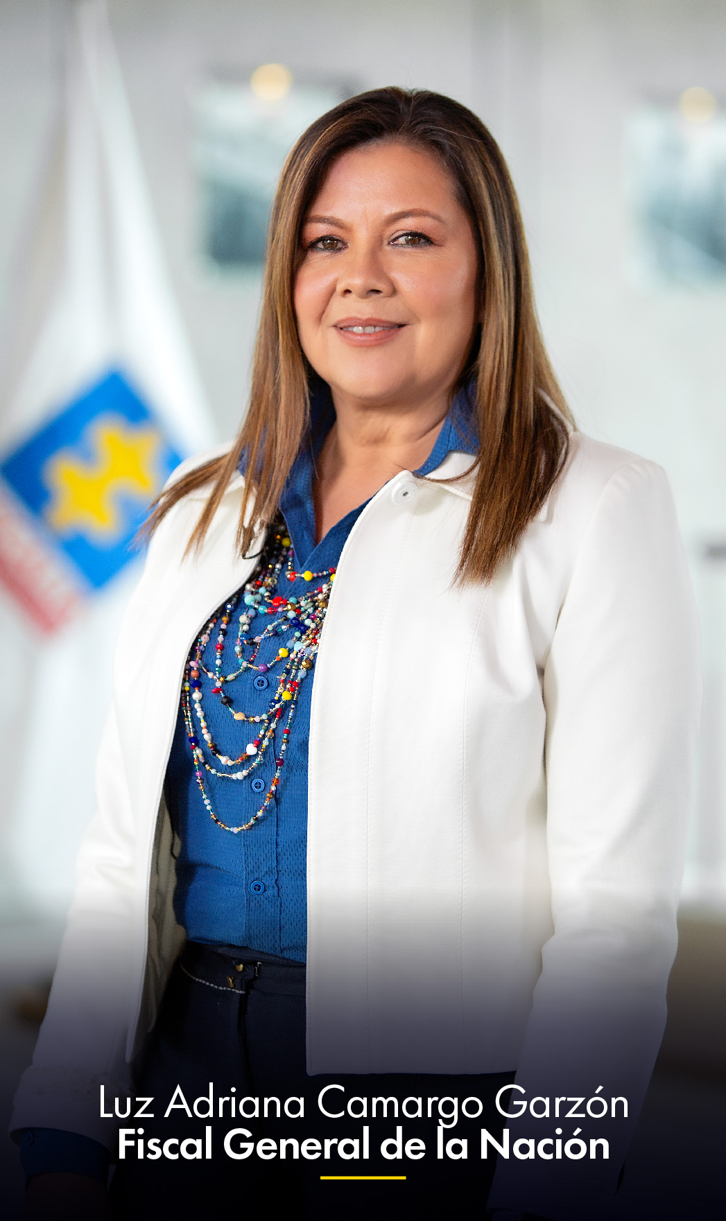 En la imagen aparece Luz Adriana Camargo Garzón, Fiscal General de la Nación, en una imagen de medio cuerpo, sonriente mirando a la cámara. Al fondo se ve una bandera de la Fiscalía.