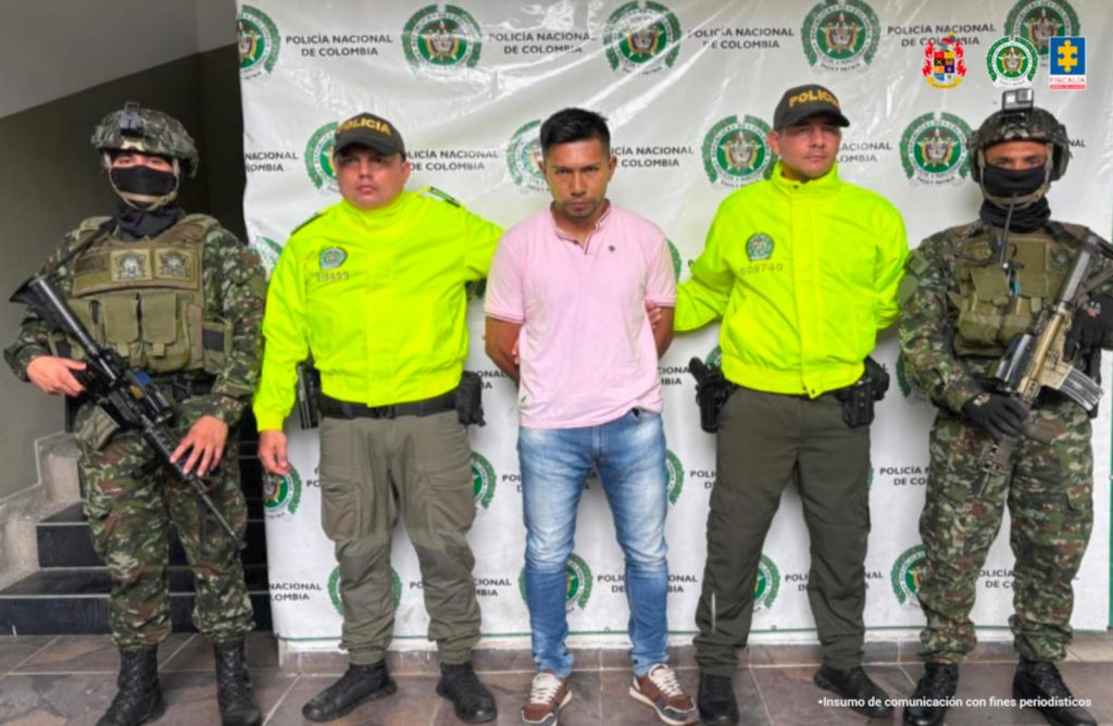 En la fotografía se aprecia de pie y con los brazos atrás a Manuel Andrés Sánchez Campo, alias Julián o Pirry. Viste camisa de color rosado, manga corta y cuello; así como jean azul desgastado y zapatillas color marrón con azul y blanco. A sus extremos hay uniformados del Ejército y de la Policía Nacional. Detrás de ellos hay un pendón institucional de la Policía.