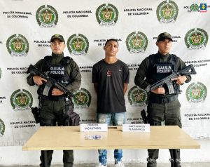 En la fotografía aparece el capturado junto a dos uniformados de la Policía NacionaI. En la parte superior está un banner de la Policía