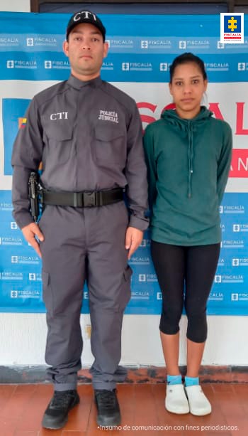 En la foto aparece, de pie y con los brazos atrás Mariana María Garcés Chirinos. Viste buzo verde, lycra negra  y zapatos blancos con medias azul claro. A su derecha hay un servidor del CTI de la Fiscalía y detrás de ellos hay un pendón institucional de la Fiscalía.