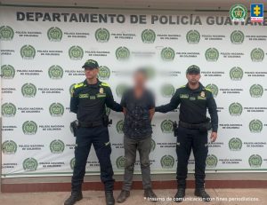 capturados de manera indivicual de frente custodiados por policía. Detrás banner de la Policía Nacional.