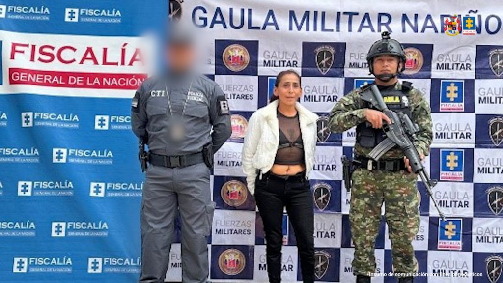 En la fotografía se aprecia de pie y con los brazos atrás a Mariela Ceballos Cedeño. Viste con blusa ombliguera, de color negro y transparente; blazer de manga larga, recortado a la cintura, de color beage; pantalón negro y zapatillas blancas. Al extremo derecho de ella hay un servidor del CTI de la Fiscalía y al izquierdo hay un uniformado del Ejército Nacional. Detrás de ellos hay dos pendones. Uno de la Fiscalía y otro del Gaula Militar con logos del Ejército y Fiscalía.